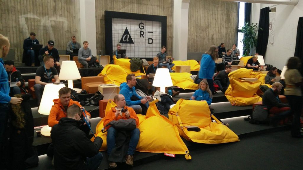 A view of people sitting in yellow couches at the Contributor day. 